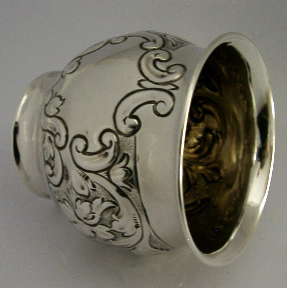 An Edwardian sterling silver fern pot featuring detailed embossed acanthus leaf and scroll decoration around the body with a polished flared rim. View VI
