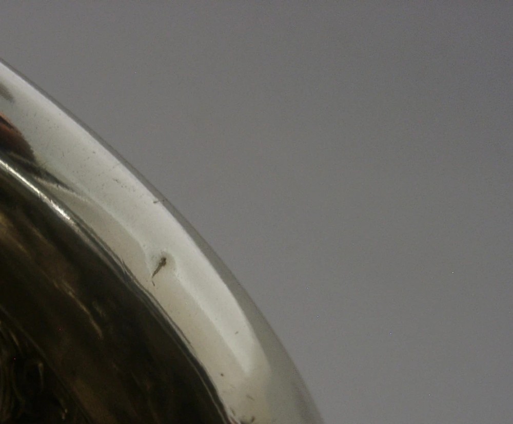 An Edwardian sterling silver fern pot featuring detailed embossed acanthus leaf and scroll decoration around the body with a polished flared rim. View XII