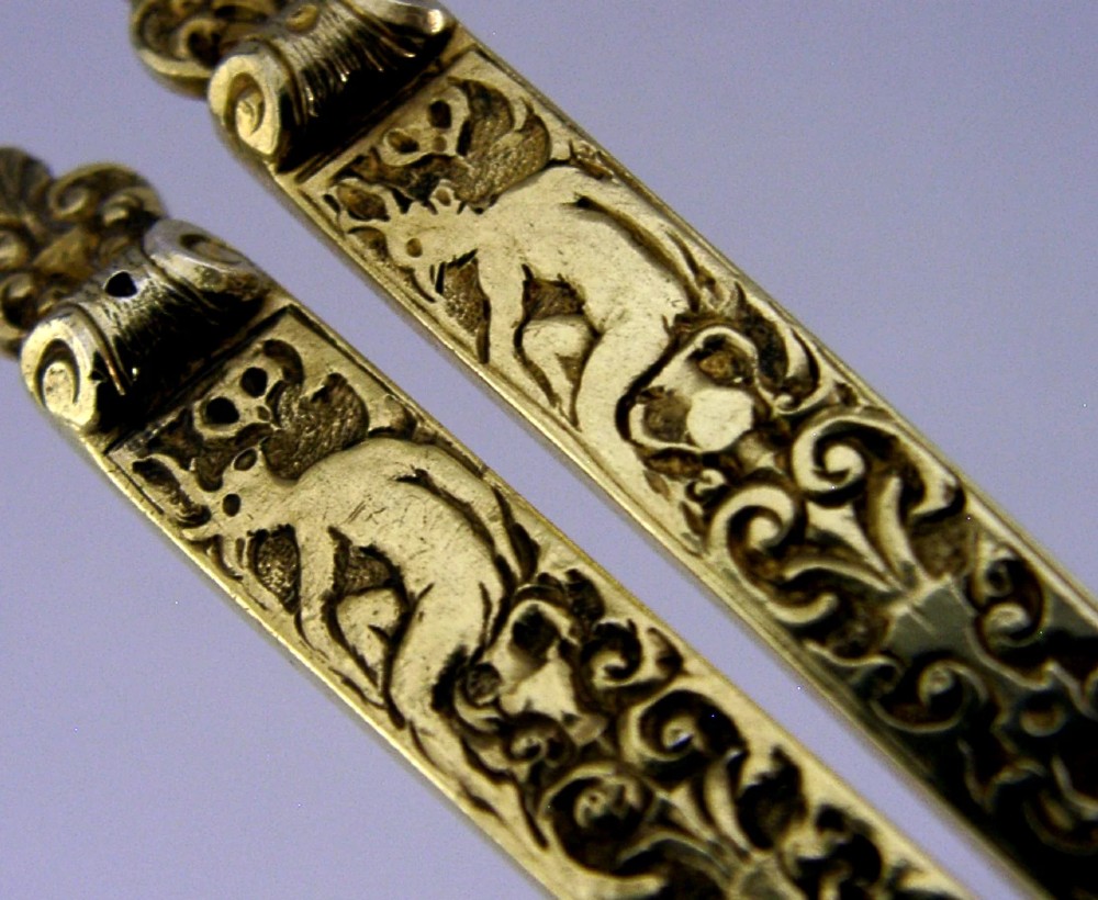 A pair of Victorian sterling silver gilt serving spoons featuring oval bowls and detailed cast handles with grotesque mask and scroll motifs. View II