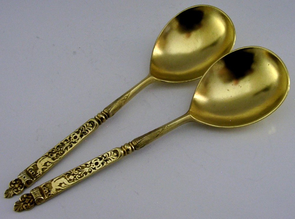 A pair of Victorian sterling silver gilt serving spoons featuring oval bowls and detailed cast handles with grotesque mask and scroll motifs. View III