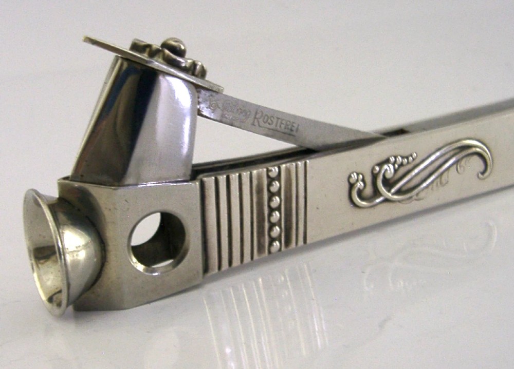 A mid-century sterling silver cigar cutter featuring a textured casing with a raised scroll motif and a stainless steel cutting blade. View II