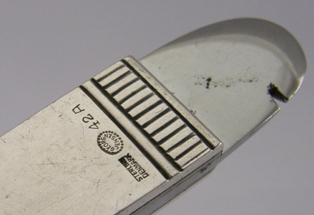 A mid-century sterling silver cigar cutter featuring a textured casing with a raised scroll motif and a stainless steel cutting blade. View XIII