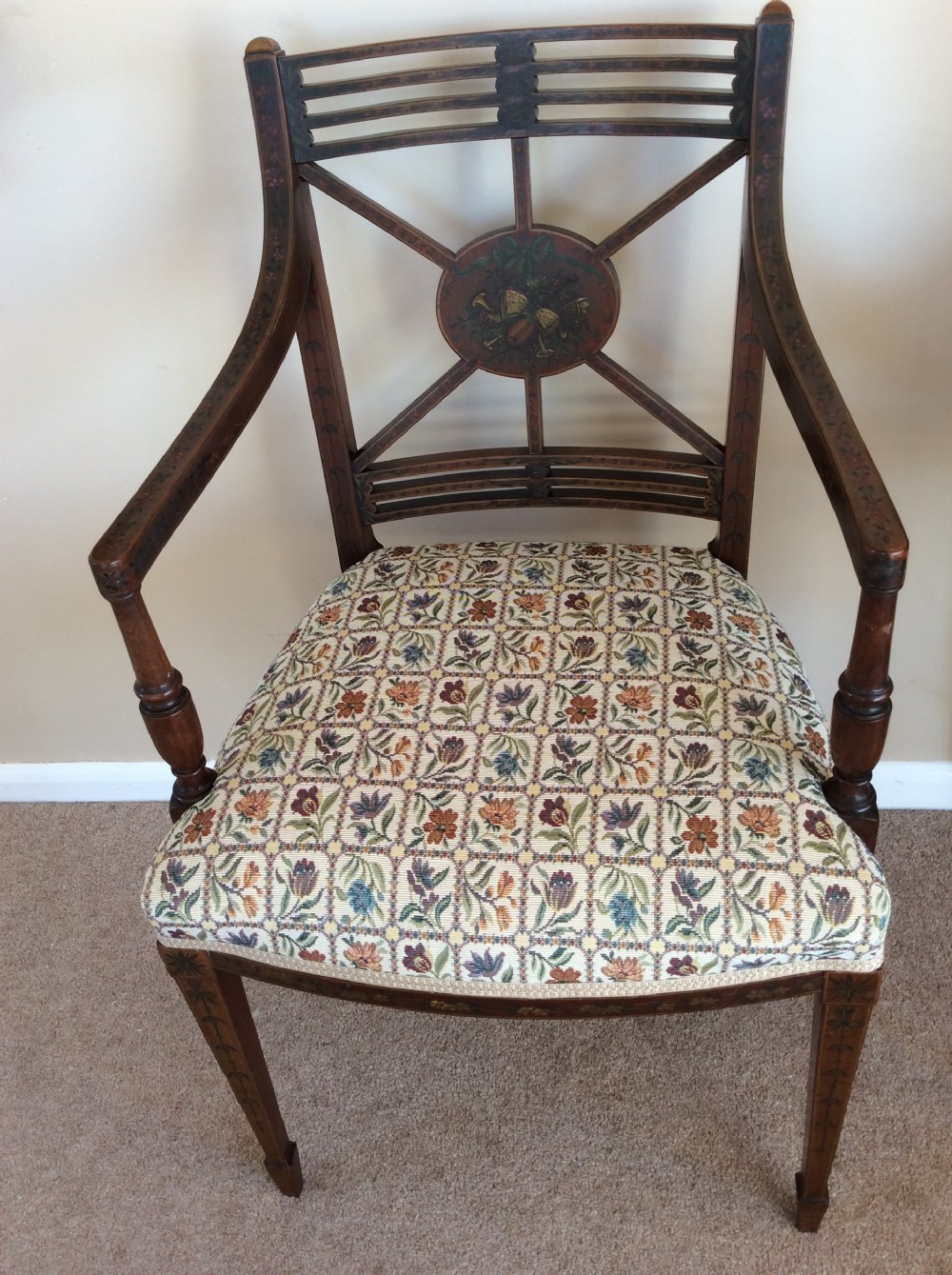 A Georgian open elbow chair with dark wood frame featuring hand-painted floral and musical motifs, an X-shaped back splat with central roundel, and a floral patterned upholstered seat.