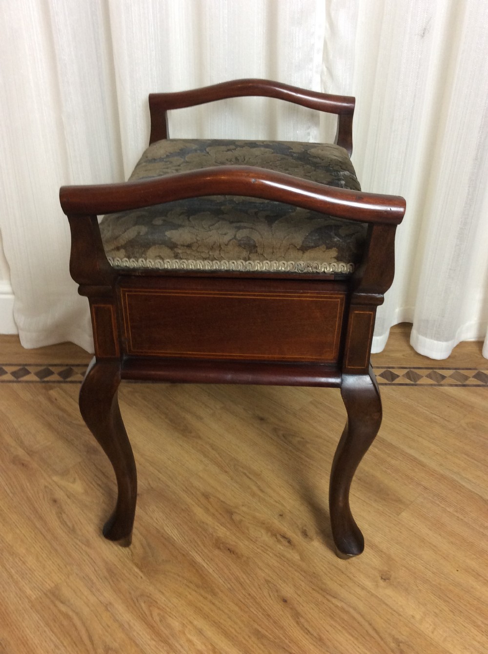 An Edwardian mahogany piano stool with raised side handles, satinwood line inlay, cabriole legs, and a dark patterned velvet upholstered seat. View III