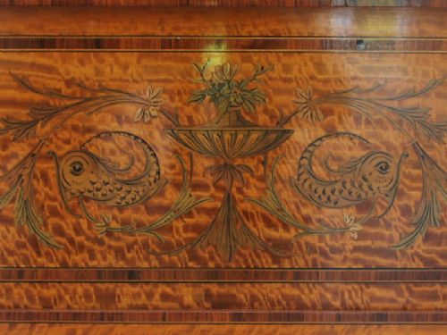 A late Victorian satinwood display cabinet featuring three glazed doors, detailed marquetry inlay, fabric-lined interior shelves, and splayed legs. View II