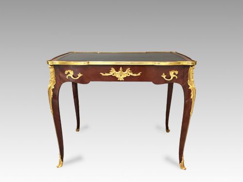 fig 3. A French Louis XV style bureau plat crafted from dark polished wood with serpentine cabriole legs, elaborate gilt-bronze ormolu mounts, and a black leather writing top.