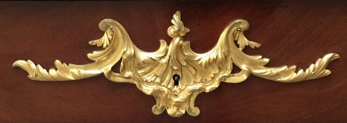 fig 4. A French Louis XV style bureau plat crafted from dark polished wood with serpentine cabriole legs, elaborate gilt-bronze ormolu mounts, and a black leather writing top.