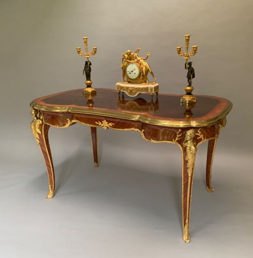 fig 1. A French Louis XV style kingwood and rosewood centre table featuring serpentine edges, cabriole legs, and gilt-bronze mounts with female bust caryatids.