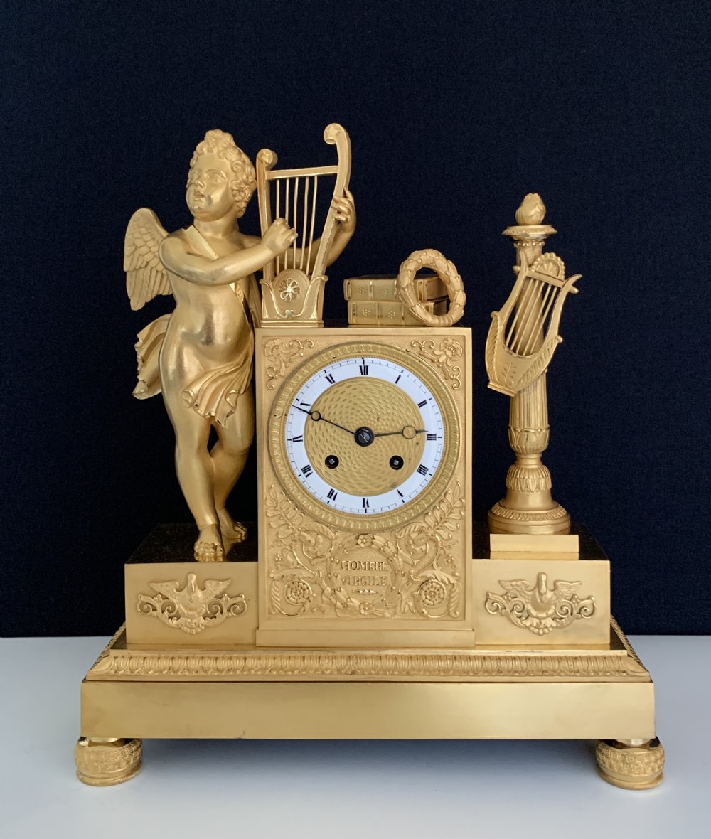 A 19th-century French Empire gilt bronze mantel clock featuring a cherub figure holding a lyre alongside classical decorative elements.