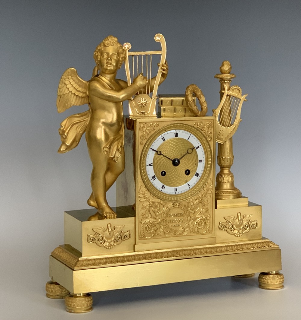 A 19th-century French Empire gilt bronze mantel clock featuring a cherub figure holding a lyre alongside classical decorative elements. View III