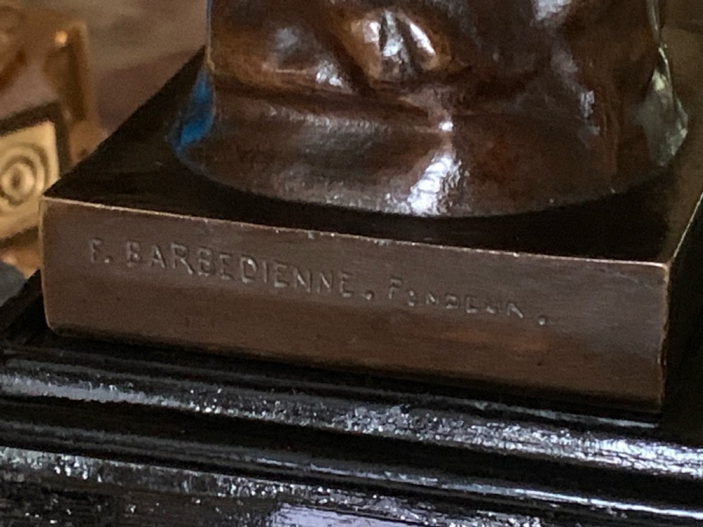 A dark patinated bronze sculpture depicting a nude youth seated on a rock, leaning forward to remove a thorn from his foot, set upon a rectangular bronze base. View VII