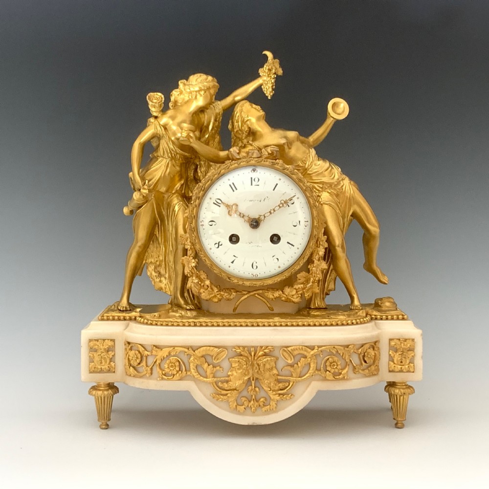 A Louis XVI style French ormolu and white marble mantel clock depicting two sculptural classical female figures flanking a circular white enamel dial. View III