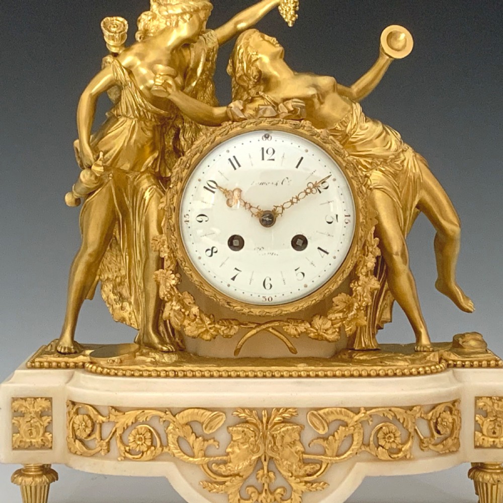 A Louis XVI style French ormolu and white marble mantel clock depicting two sculptural classical female figures flanking a circular white enamel dial. View V