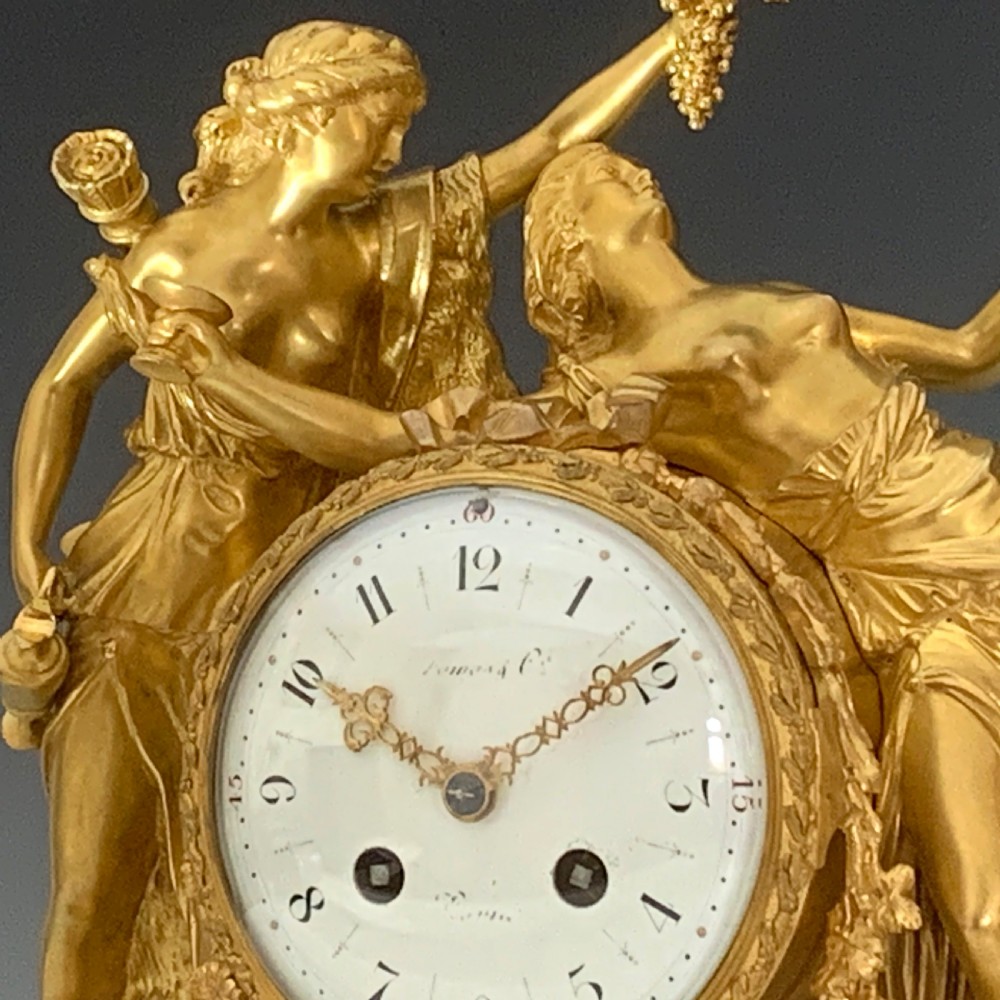 A Louis XVI style French ormolu and white marble mantel clock depicting two sculptural classical female figures flanking a circular white enamel dial. View VII