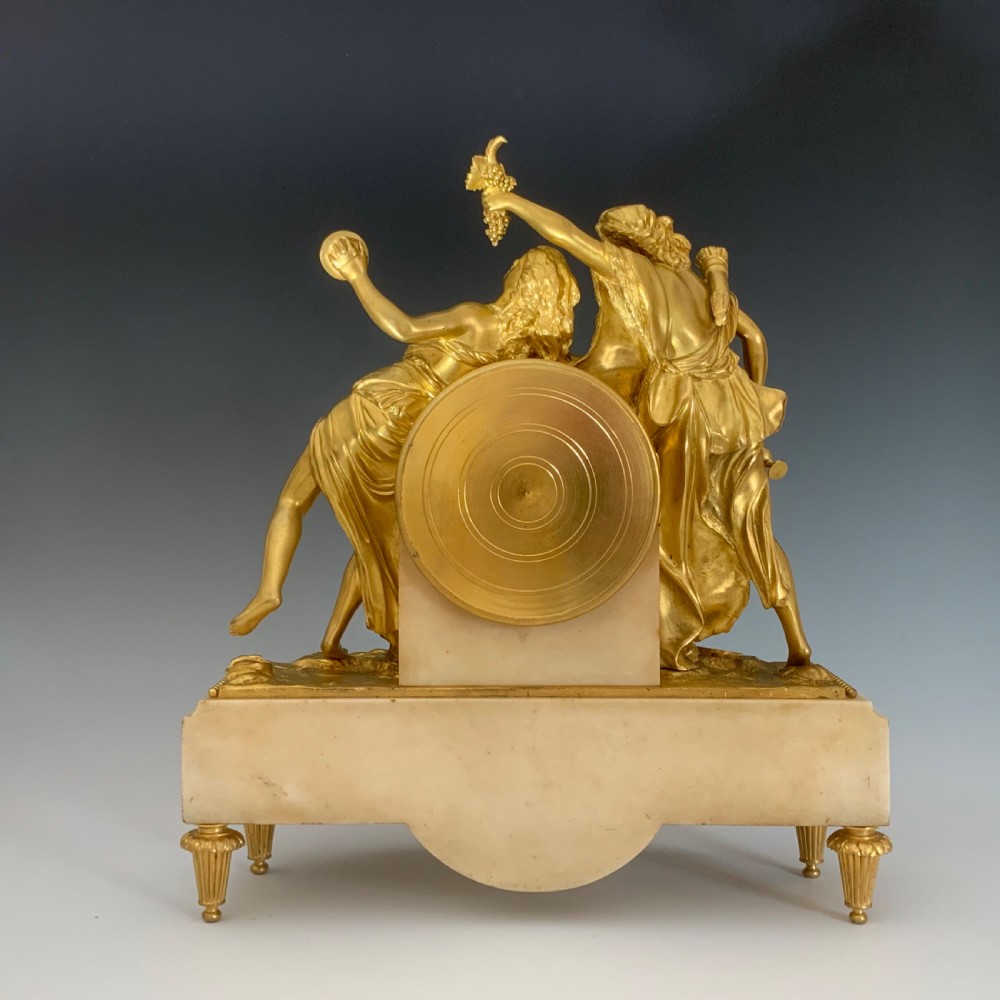 A Louis XVI style French ormolu and white marble mantel clock depicting two sculptural classical female figures flanking a circular white enamel dial. View X