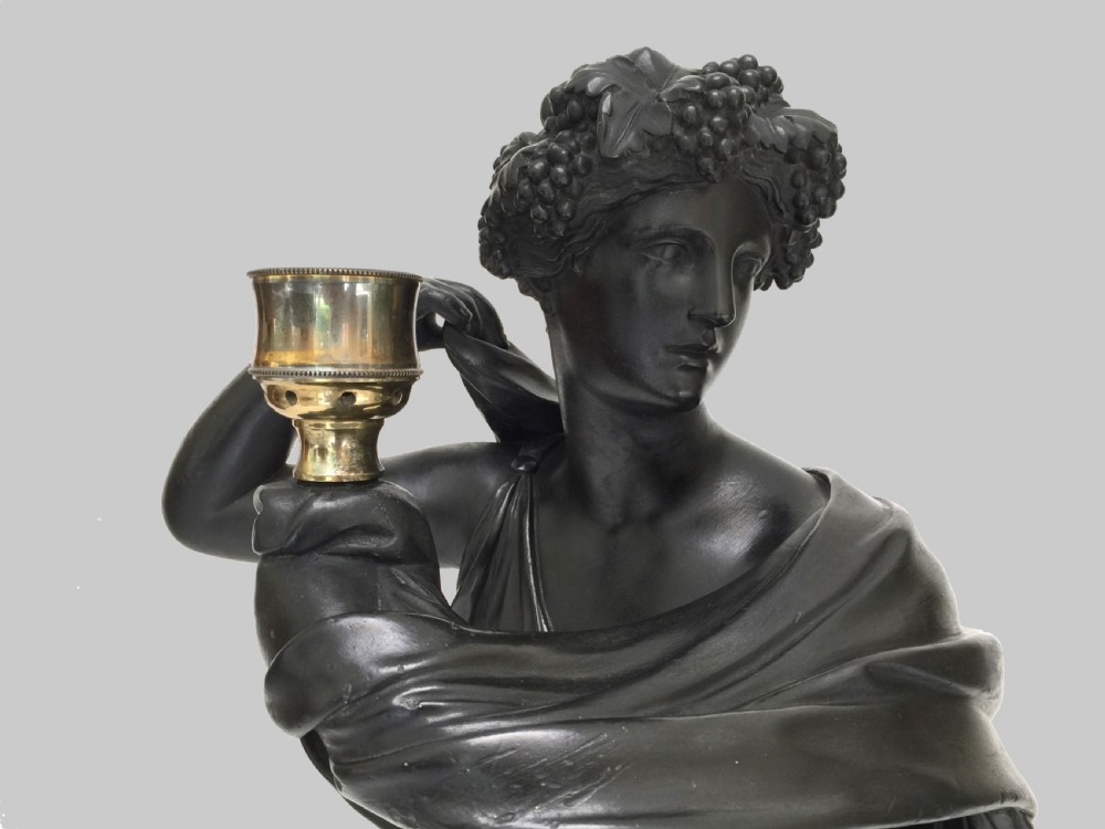 A dark patinated plaster figure of a classical muse holding a glass hurricane shade, set upon a tall square painted plinth with blue trim. View III