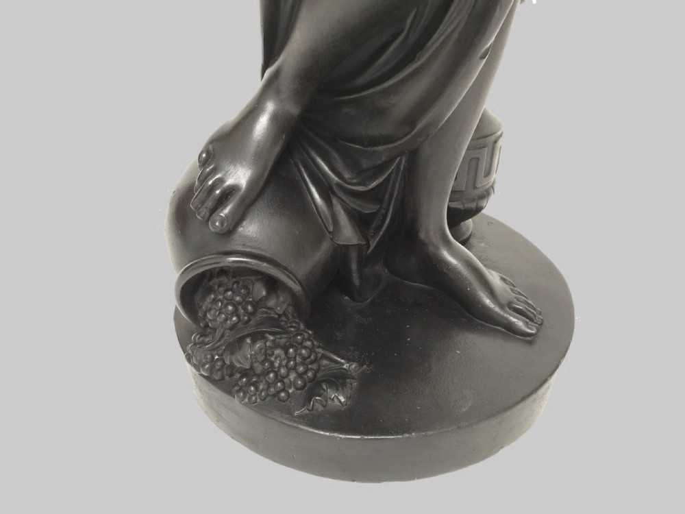 A dark patinated plaster figure of a classical muse holding a glass hurricane shade, set upon a tall square painted plinth with blue trim. View IV