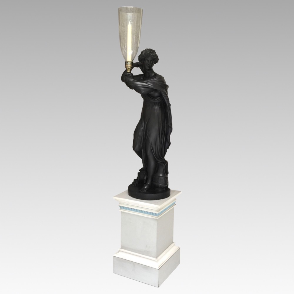 A dark patinated plaster figure of a classical muse holding a glass hurricane shade, set upon a tall square painted plinth with blue trim. View V