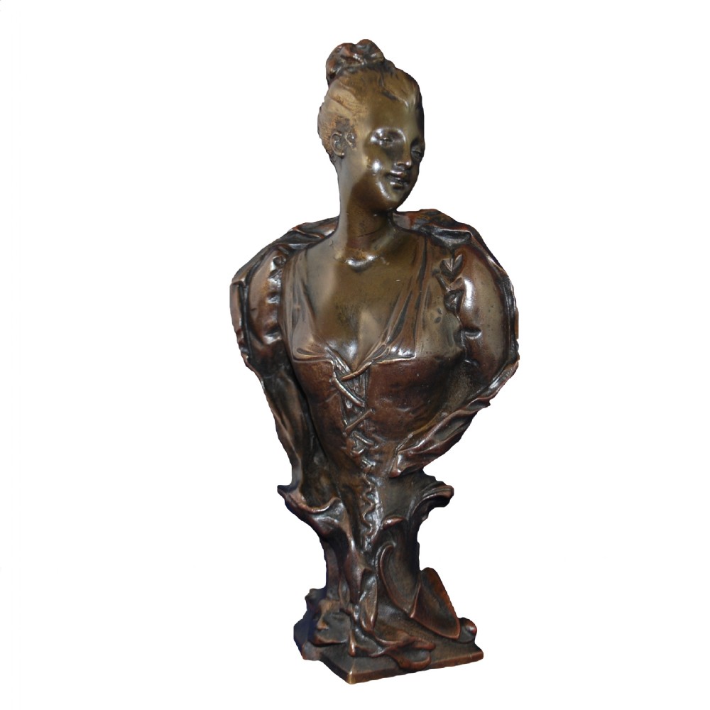 A cast bronze Art Nouveau bust depicting a young woman with swept-up hair and a laced bodice on an integrated base.