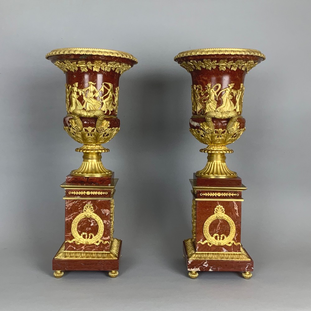 A pair of red marble urns featuring gilt bronze mounts, classical relief friezes of dancing figures, and pedestal bases decorated with lyres. View VII