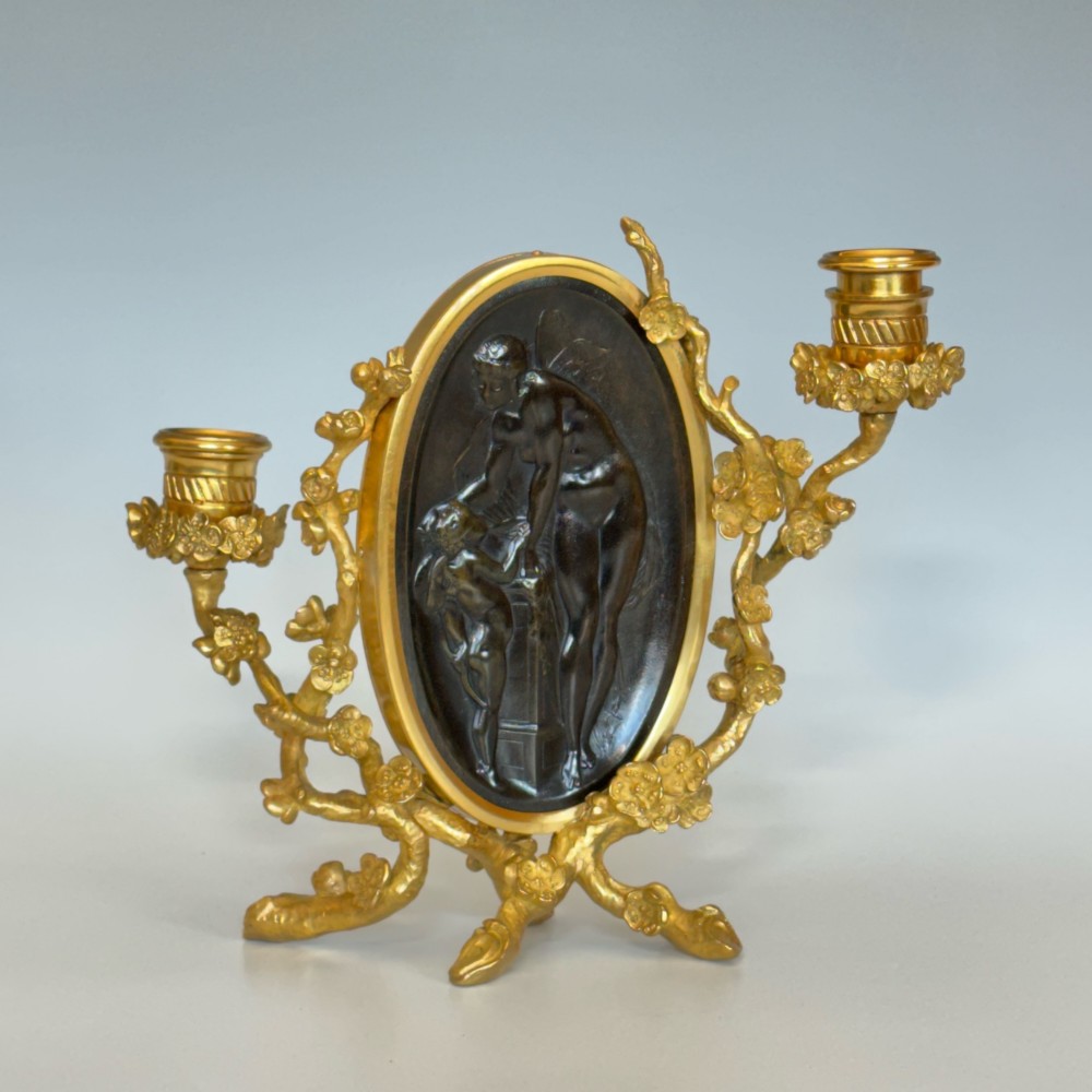 A French 19th-century gilt bronze table frame featuring a central oval classical relief medallion flanked by two candelabra arms with organic floral branching.