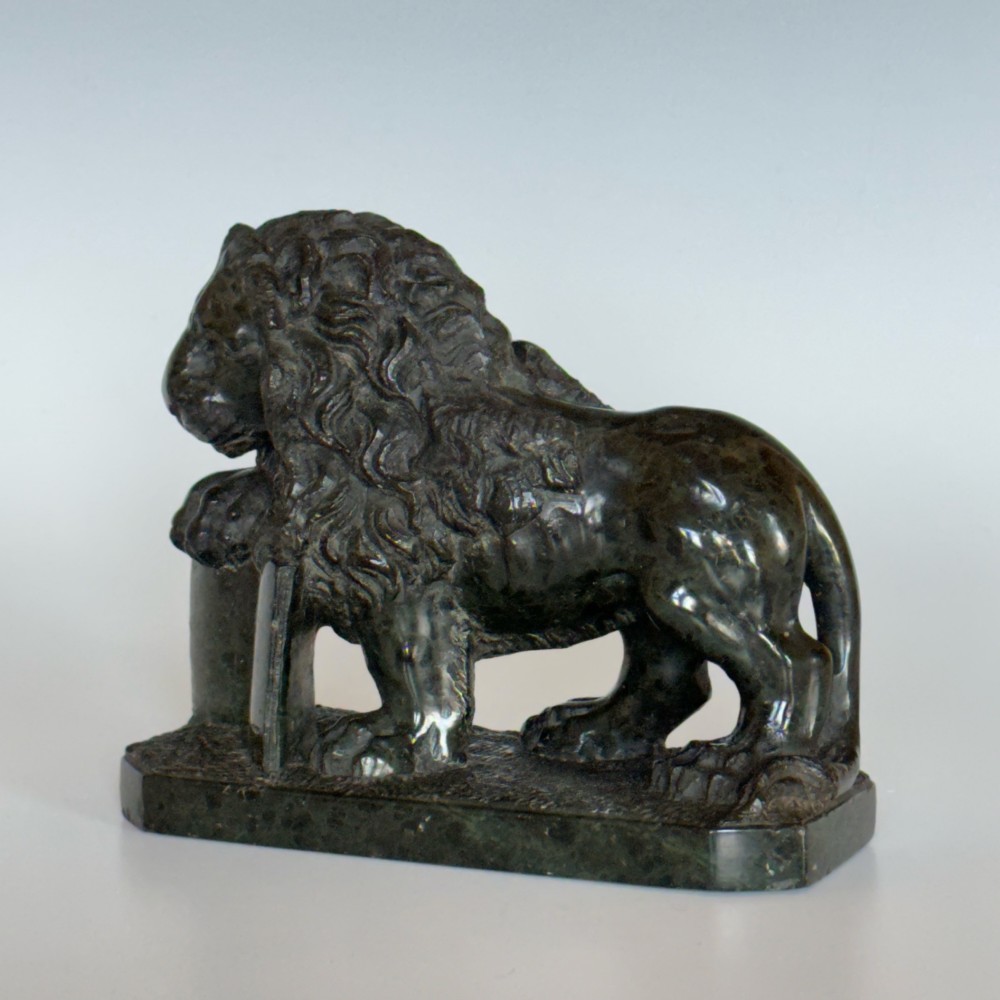 A dark green carved serpentine marble sculpture depicting the Lion of Saint Mark resting a paw on an upright book.