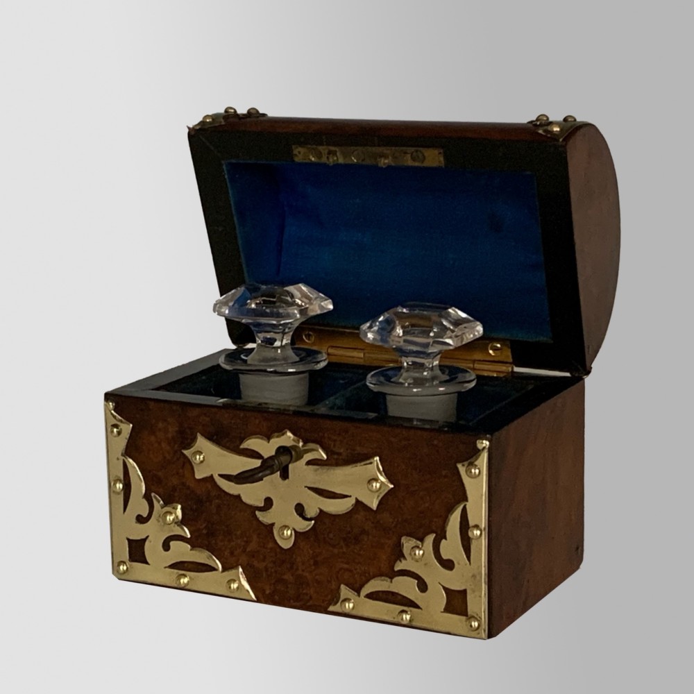 An open Victorian burr walnut scent casket with brass corner mounts containing two cut glass perfume bottles lined with blue fabric. View III