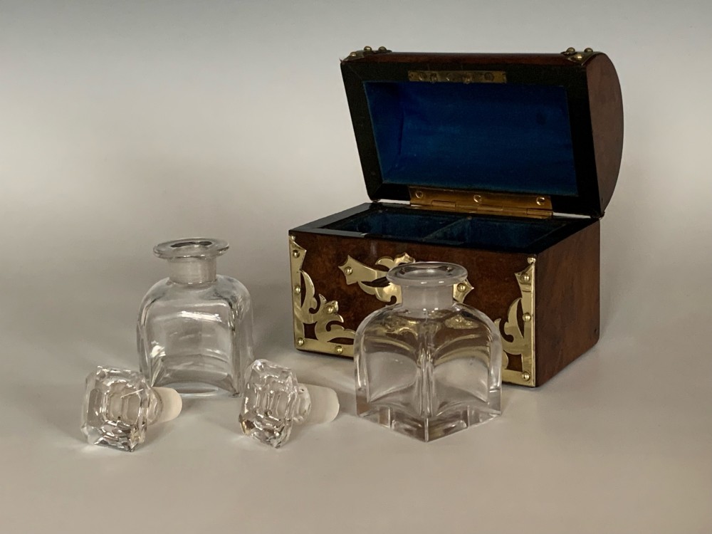 An open Victorian burr walnut scent casket with brass corner mounts containing two cut glass perfume bottles lined with blue fabric. View IV