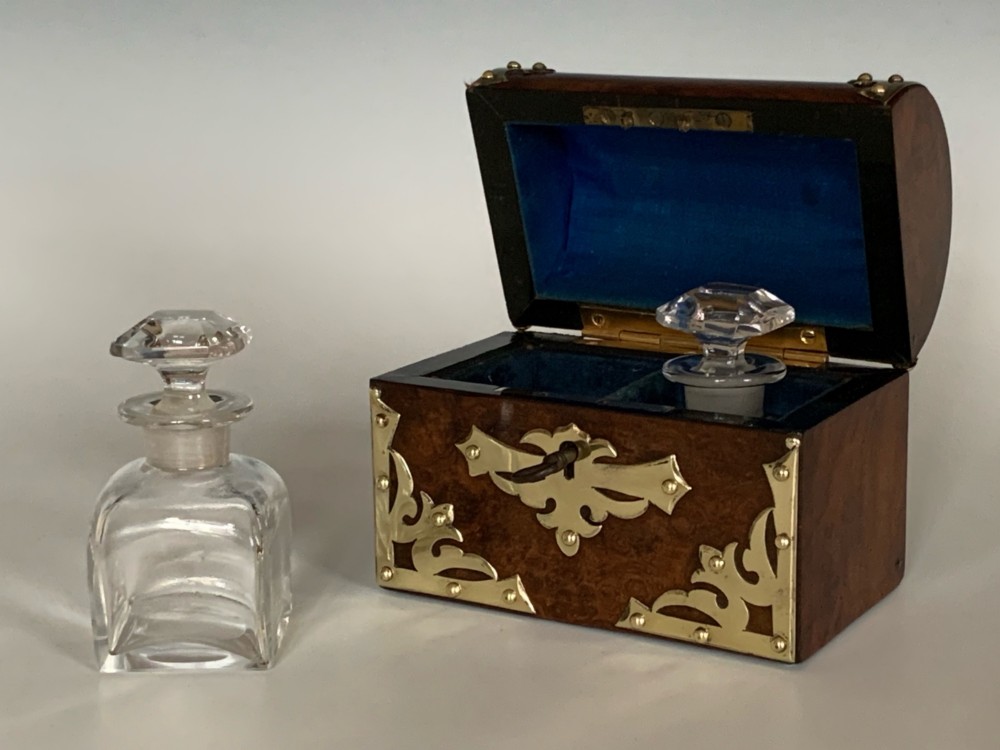 An open Victorian burr walnut scent casket with brass corner mounts containing two cut glass perfume bottles lined with blue fabric. View V