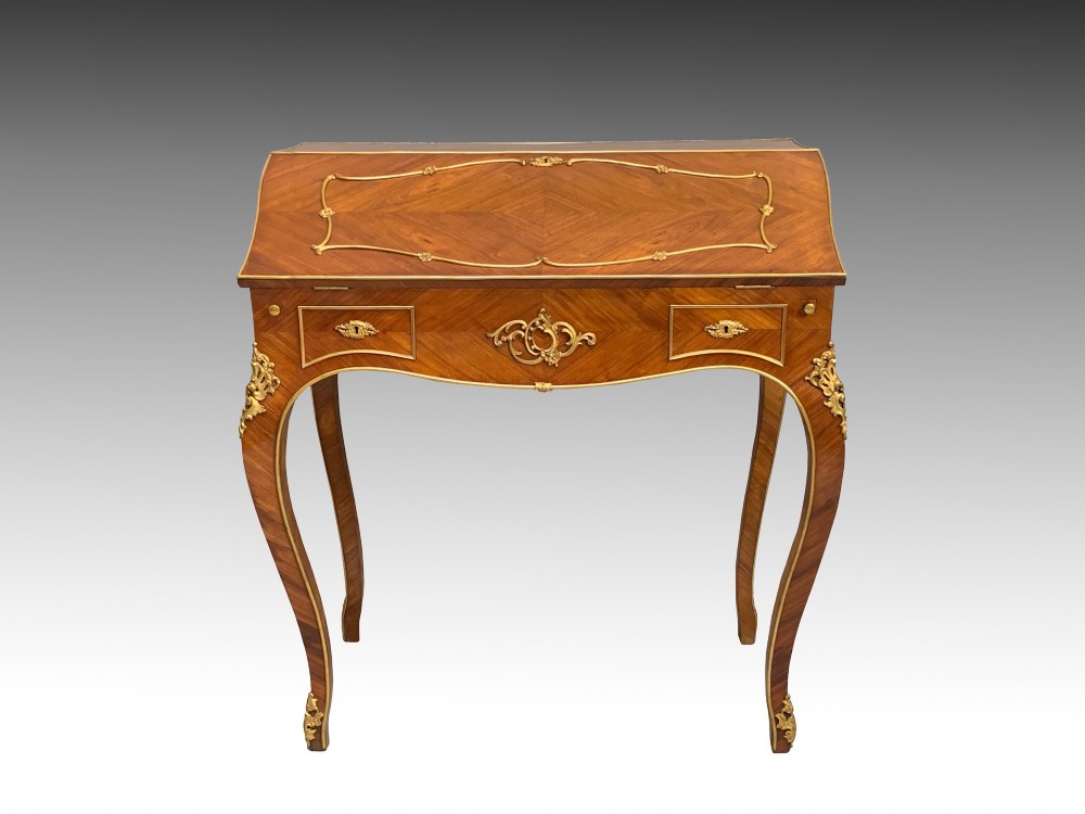 A 19th-century French Napoleon III tulipwood bureau featuring a slant top with brass inlay, ormolu mounts, and cabriole legs.