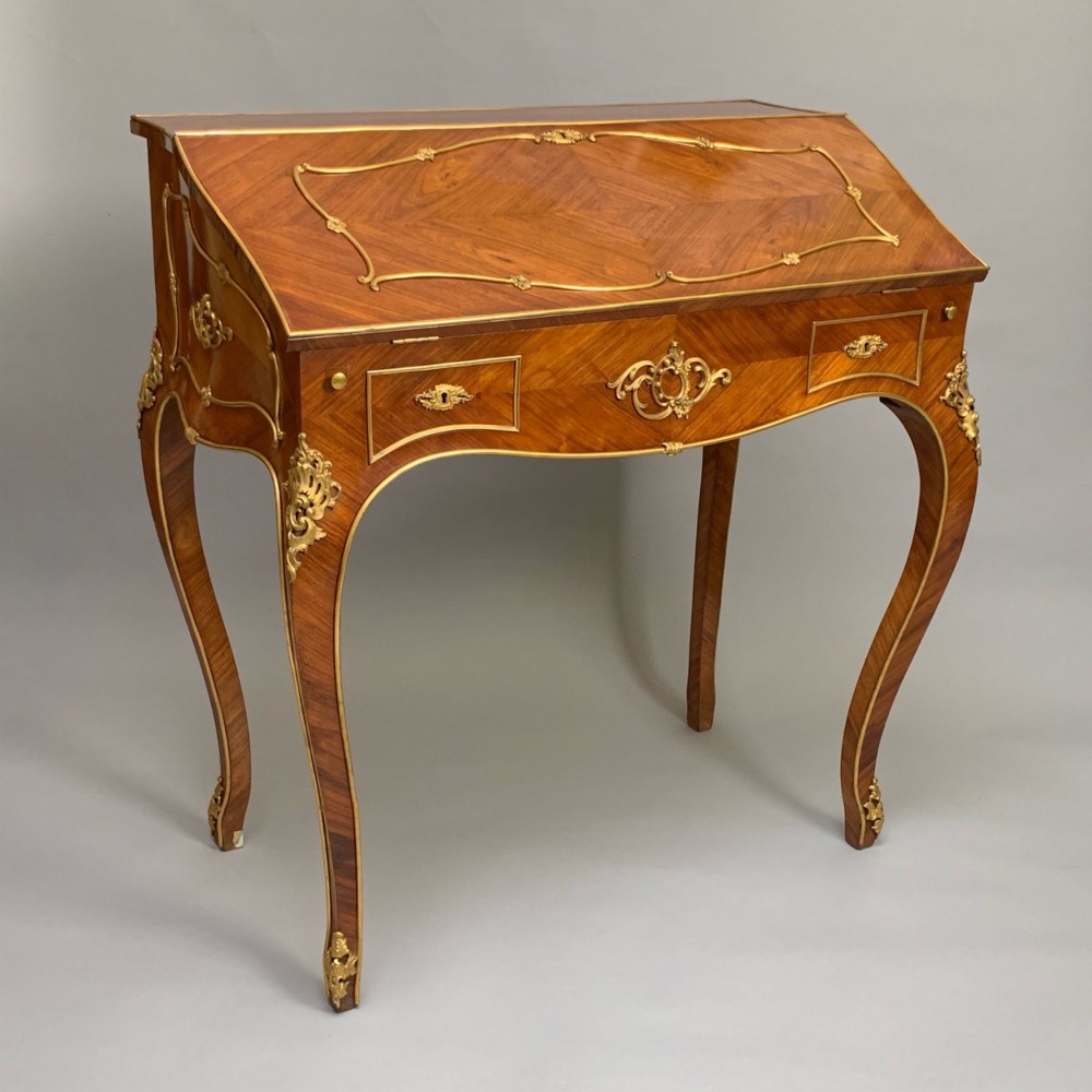 A 19th-century French Napoleon III tulipwood bureau featuring a slant top with brass inlay, ormolu mounts, and cabriole legs. View II