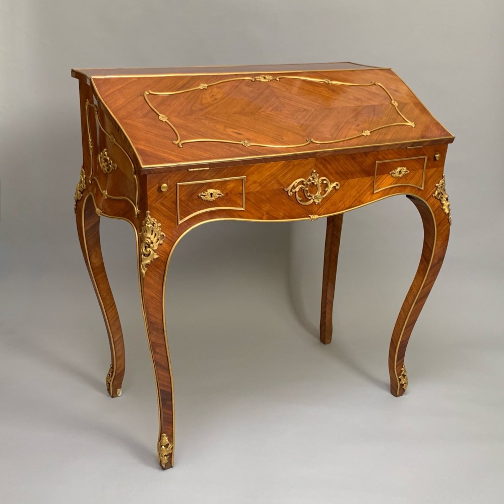 A 19th-century French Napoleon III tulipwood bureau featuring a slant top with brass inlay, ormolu mounts, and cabriole legs. View III