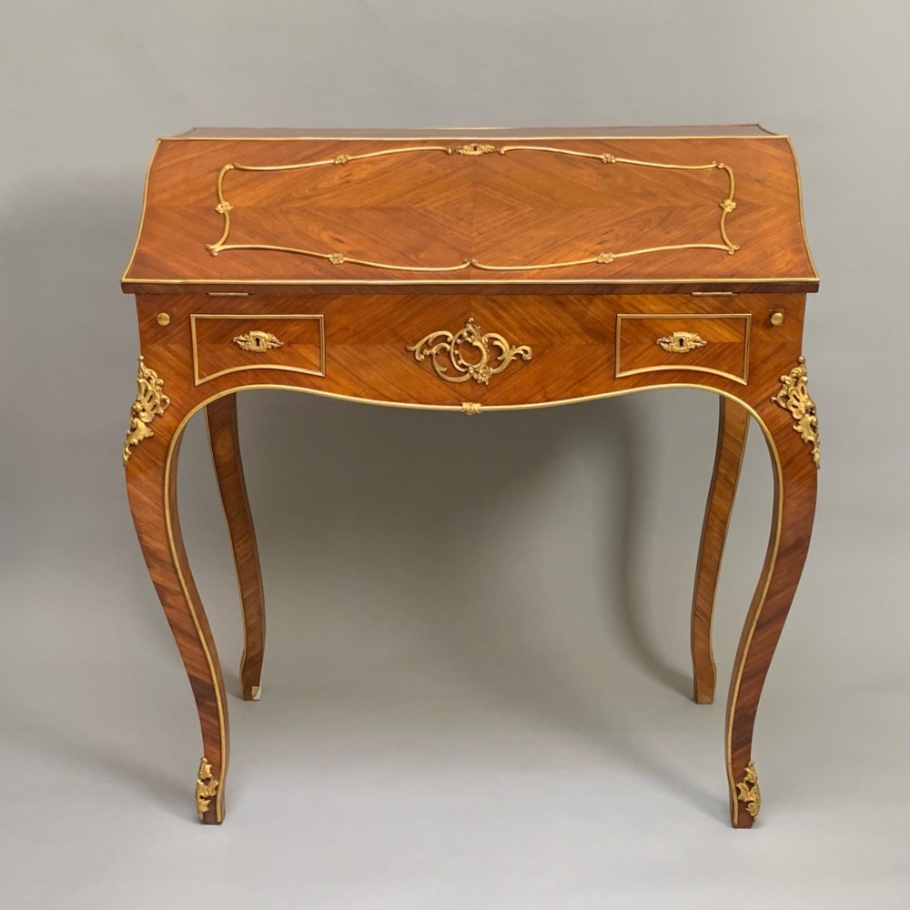 A 19th-century French Napoleon III tulipwood bureau featuring a slant top with brass inlay, ormolu mounts, and cabriole legs. View IV