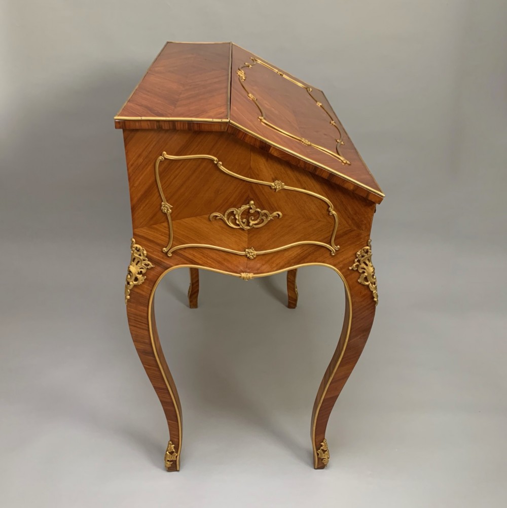 A 19th-century French Napoleon III tulipwood bureau featuring a slant top with brass inlay, ormolu mounts, and cabriole legs. View IX