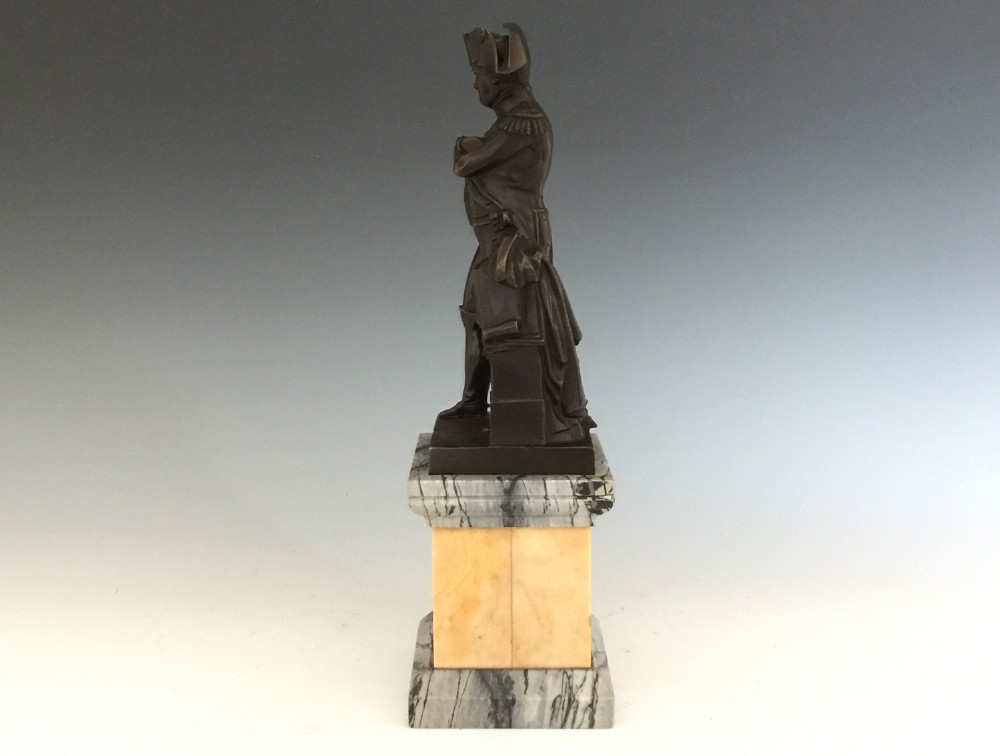 A nineteenth-century bronze figure of Napoleon Bonaparte in full military uniform standing with arms crossed on a yellow and grey marble plinth. View III