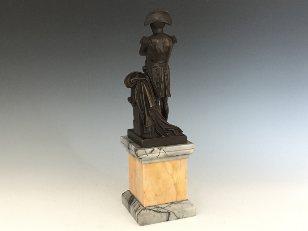 A nineteenth-century bronze figure of Napoleon Bonaparte in full military uniform standing with arms crossed on a yellow and grey marble plinth. View IV