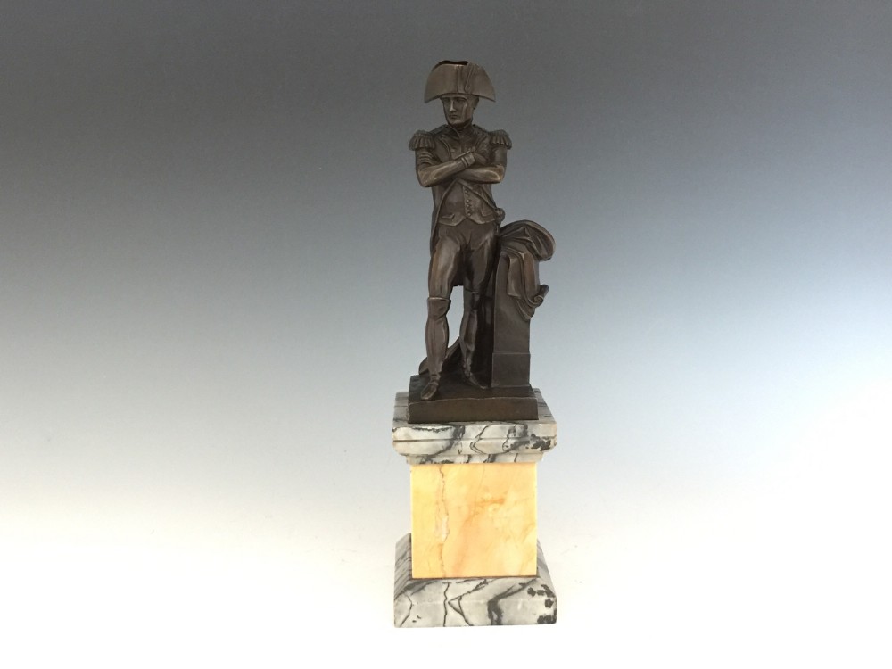 A nineteenth-century bronze figure of Napoleon Bonaparte in full military uniform standing with arms crossed on a yellow and grey marble plinth. View VII