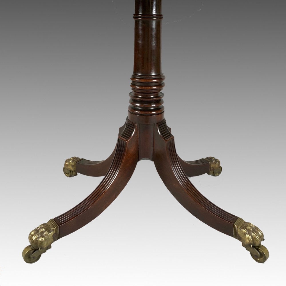 A George IV mahogany fold-over card table featuring a turned pedestal stem, geometric frieze inlay, and splayed legs with brass paw castors. View IV