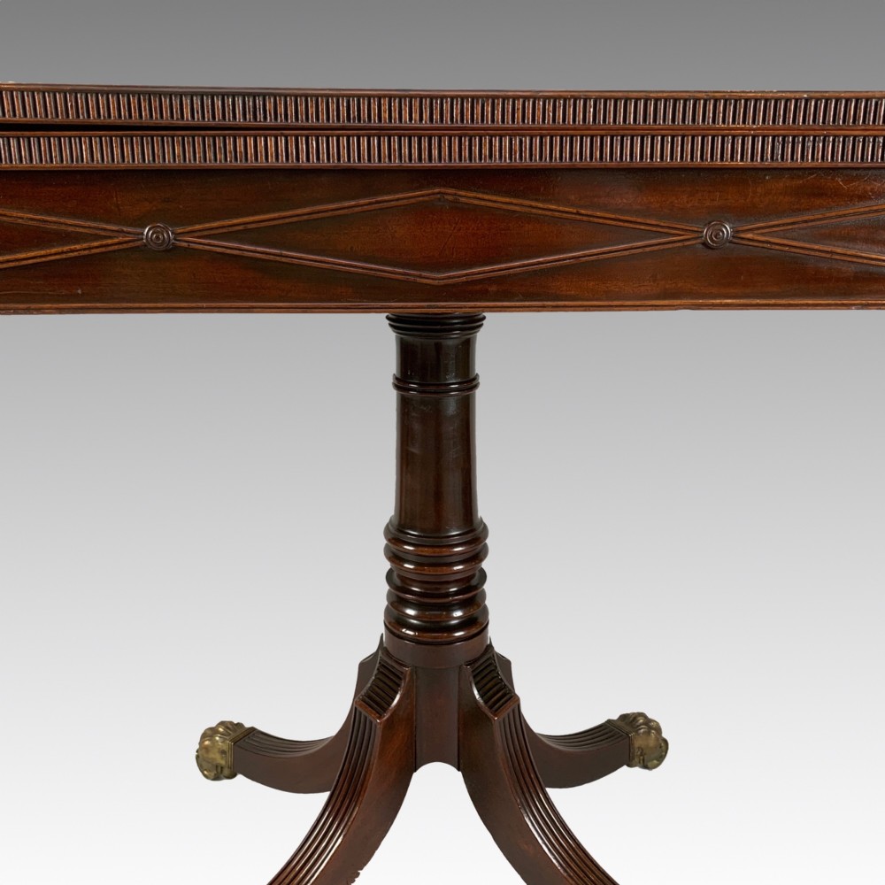 A George IV mahogany fold-over card table featuring a turned pedestal stem, geometric frieze inlay, and splayed legs with brass paw castors. View V