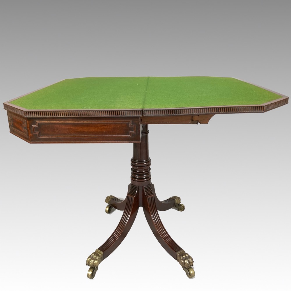 A George IV mahogany fold-over card table featuring a turned pedestal stem, geometric frieze inlay, and splayed legs with brass paw castors. View X