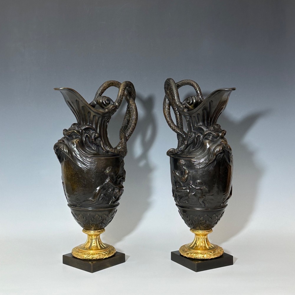 A pair of dark patinated bronze French ewers featuring relief carvings of classical mythological figures, serpent handles, satyr masks, and gilt bronze bases. View VII