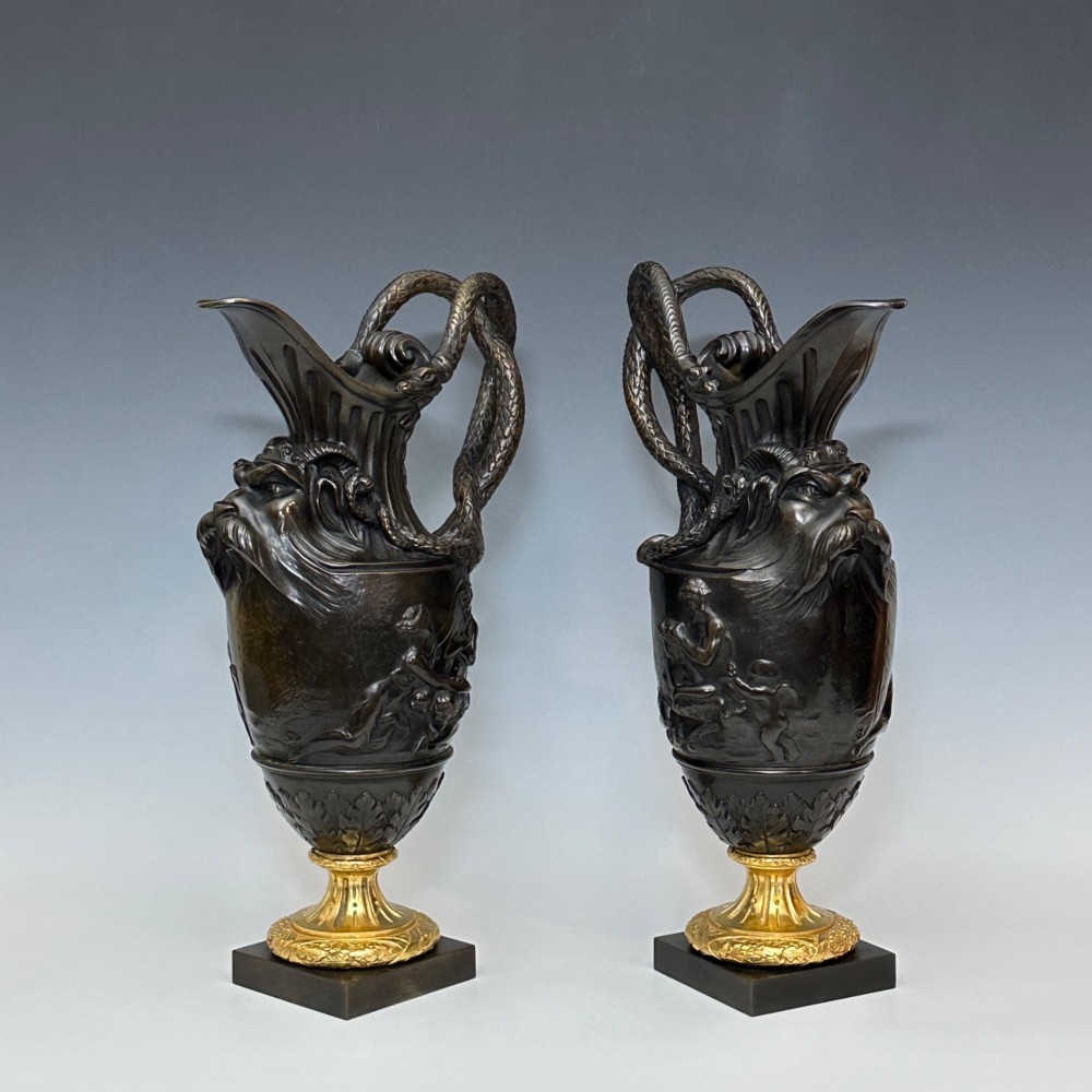 A pair of dark patinated bronze French ewers featuring relief carvings of classical mythological figures, serpent handles, satyr masks, and gilt bronze bases. View VIII