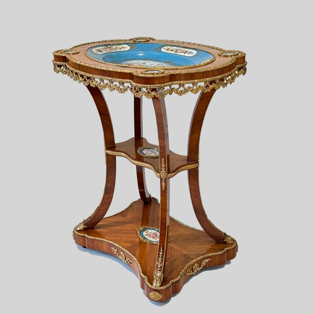 A French Napoleon III tulipwood gueridon featuring gilt-bronze mounts, a central blue Sevres-style porcelain top plaque, and two tiered shelves.