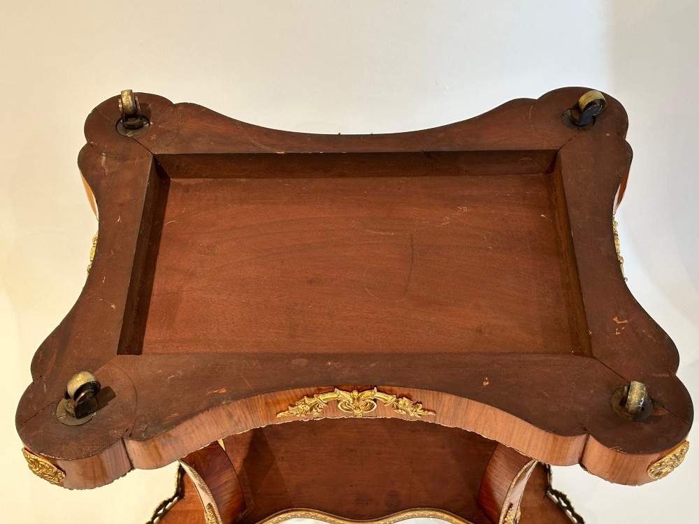 A French Napoleon III tulipwood gueridon featuring gilt-bronze mounts, a central blue Sevres-style porcelain top plaque, and two tiered shelves. View IX