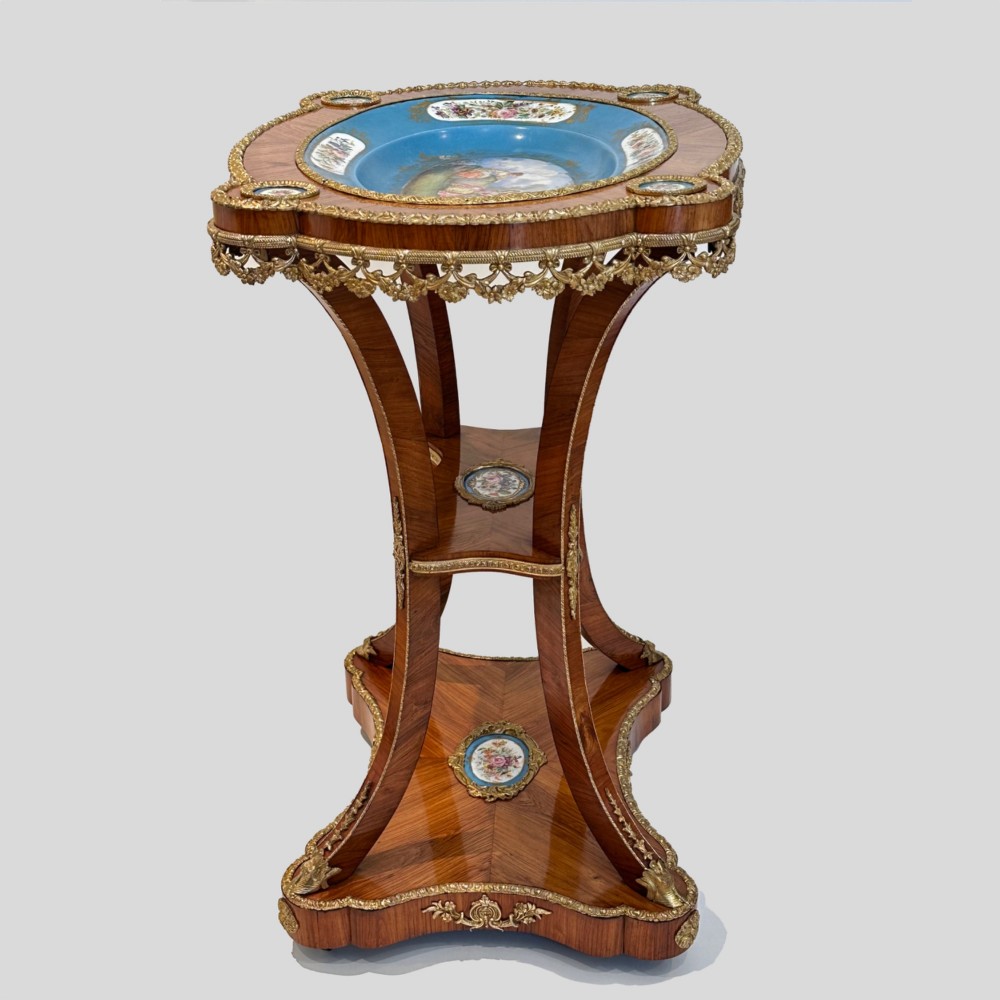 A French Napoleon III tulipwood gueridon featuring gilt-bronze mounts, a central blue Sevres-style porcelain top plaque, and two tiered shelves. View XIII