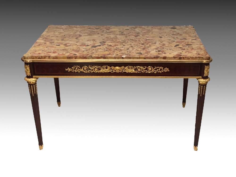 A rectangular Louis XVI style centre table featuring a variegated marble top, dark mahogany frieze with elaborate gilt bronze mounts, and four fluted tapered legs.