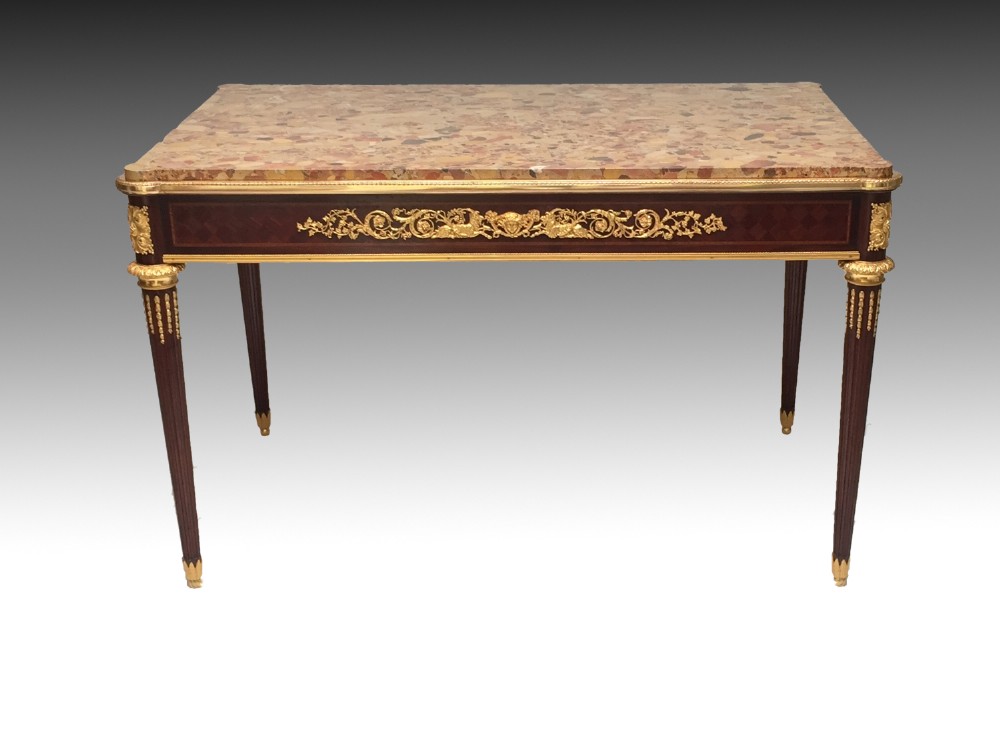 A rectangular Louis XVI style centre table featuring a variegated marble top, dark mahogany frieze with elaborate gilt bronze mounts, and four fluted tapered legs. View IV