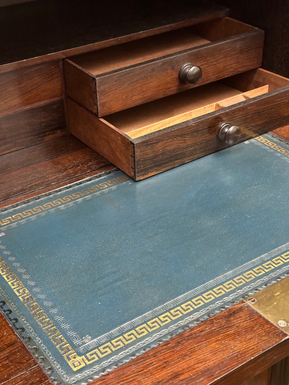 A George IV rosewood writing cabinet with a open fall-front desk revealing internal drawers and a dark green leather writing surface above lower drawers with brass handles. View VI
