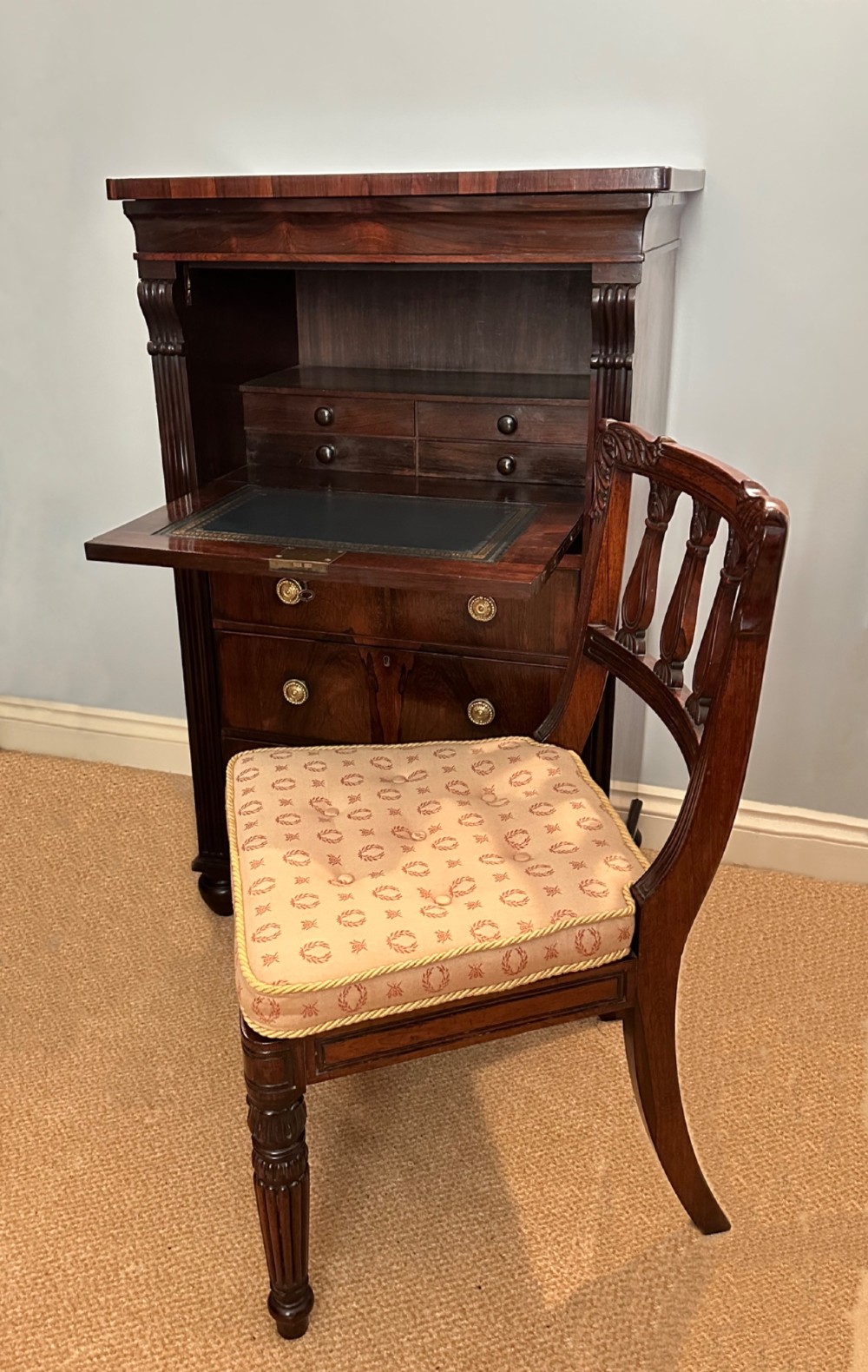 A George IV rosewood writing cabinet with a open fall-front desk revealing internal drawers and a dark green leather writing surface above lower drawers with brass handles. View X