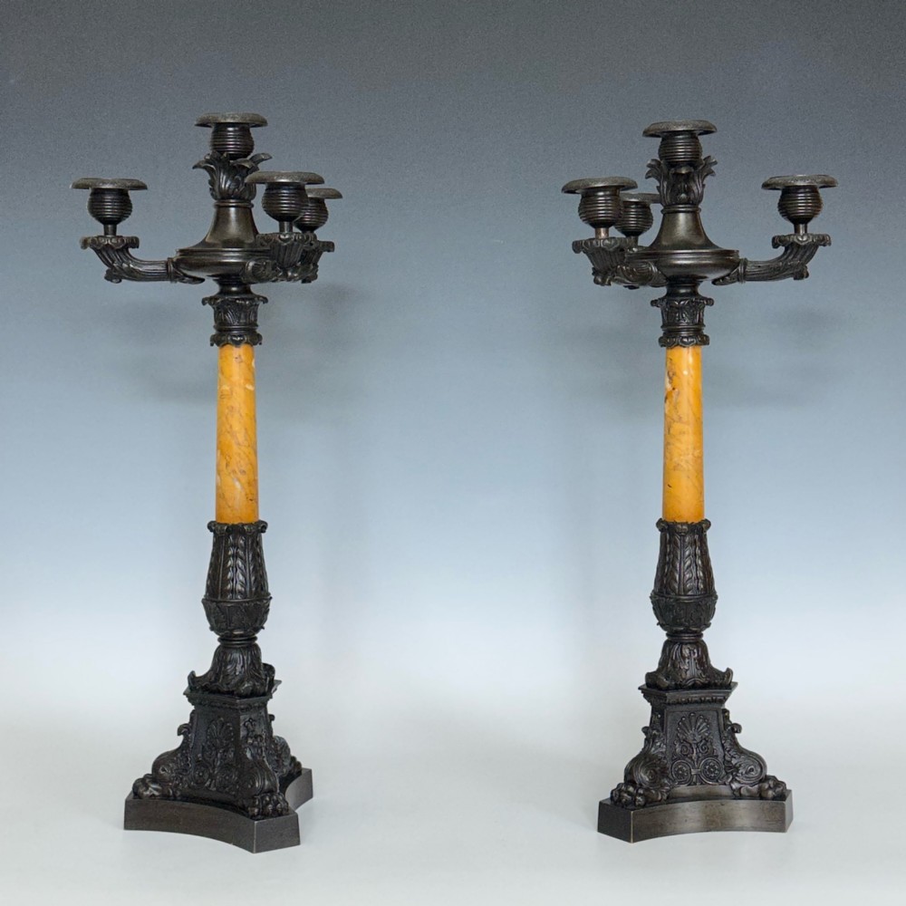 A pair of French Restoration period dark bronze candelabra with four candle branches each, supported by cylindrical yellow marble columns on detailed cast bronze tripartite bases. View V